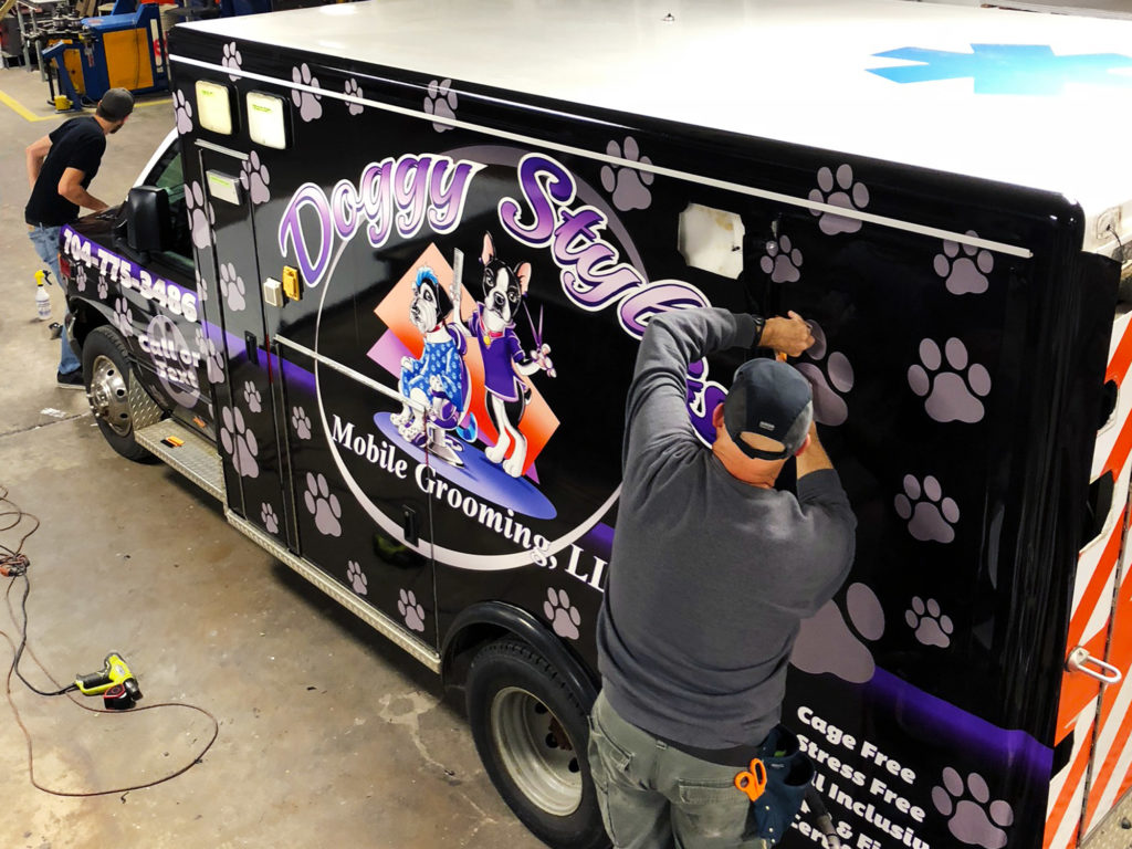 Vinyl graphics installers applying a wrap to an ambulance.
