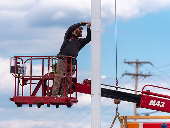 Installer on a lift prepping a pole for sign installation
