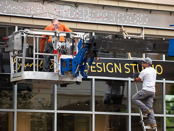 Installers lifting a sign face into place