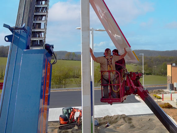 Sign service technicians in a lift repairing a cabinet sign.