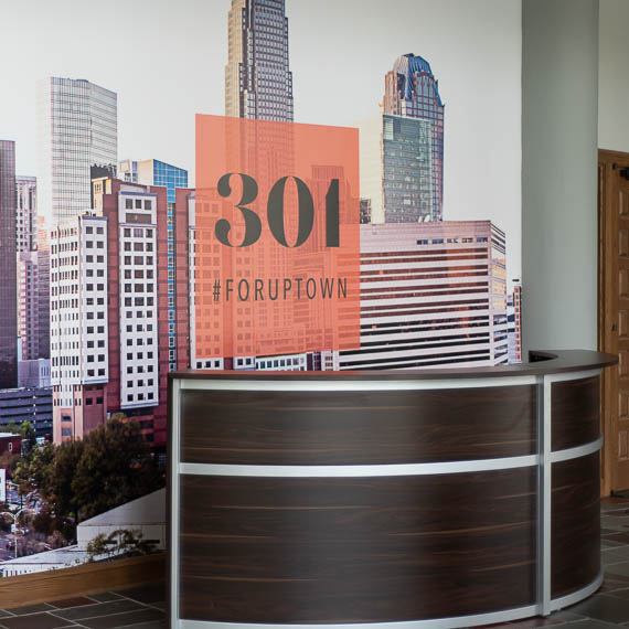 Mural of uptown Charlotte with 301 branding behind church welcome desk.
